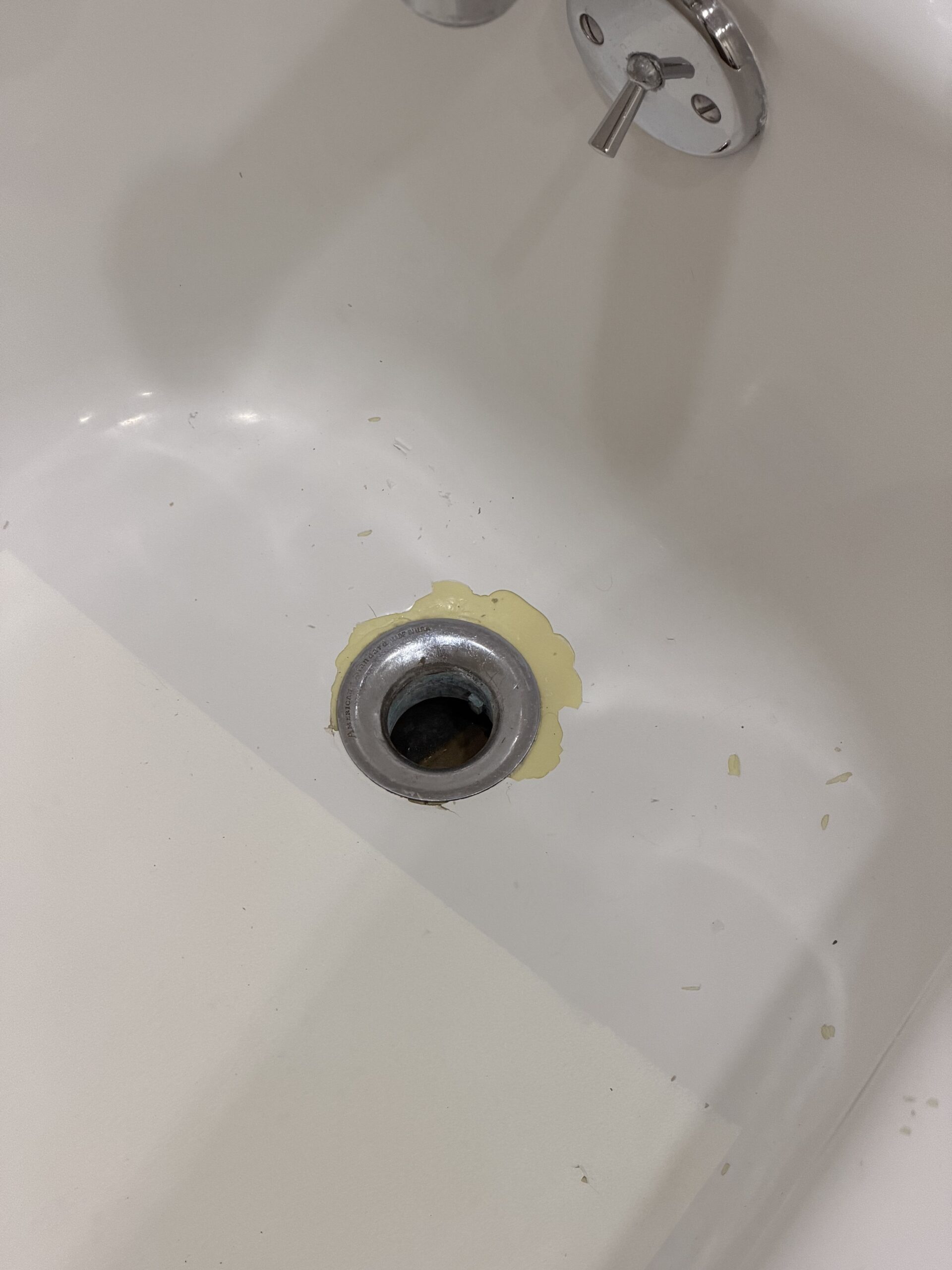 Peeling white bathtub coating around the drain before refinishing in Lincoln Park, Chicago.