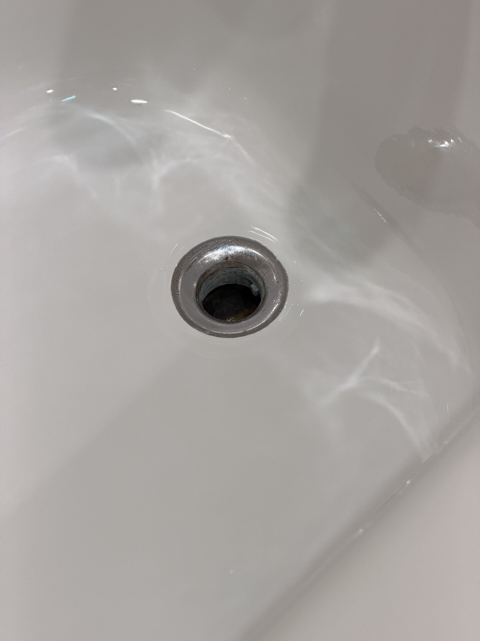 White bathtub surface around the drain after refinishing in Lincoln Park, Chicago.