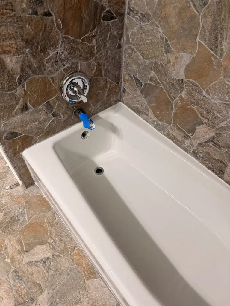 Refinished white bathtub in La Grange with tape still on the spout and the overflow cover removed.