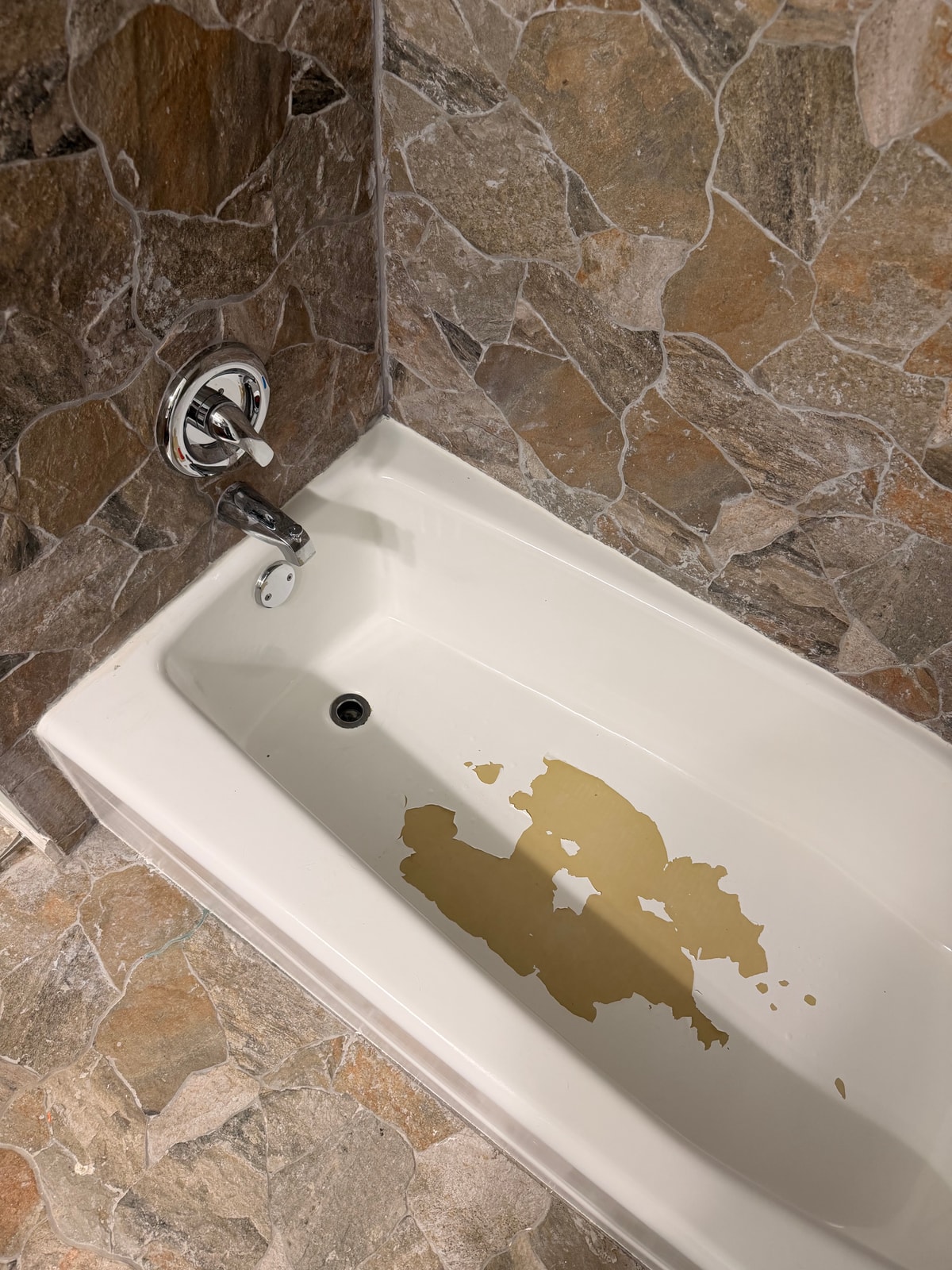 Peeling white coating across the bottom of a bathtub before refinishing in La Grange, Illinois.